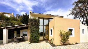 A modern house with a stone patio, a covered outdoor seating area, and a large glass window. - House for 6 people in the Valcros estate with a shared pool (LA LONDE LES MAURES)
