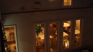 A building with multiple windows, some of which are illuminated. There are outdoor tables and chairs arranged in the foreground. - La Tipasa (Tateyama)