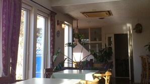 A spacious dining area with a high ceiling, large windows, and multiple hanging plants. - La Tipasa (Tateyama)