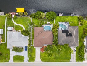 Vista aerea di una zona residenziale con piscina, campo da tennis e un grande albero.