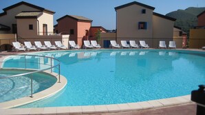 Una piscina con sillas de descanso y un suelo de baldosas.
