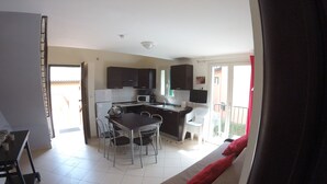 Un espacio habitable compacto con kitchenette, comedor y balcón.