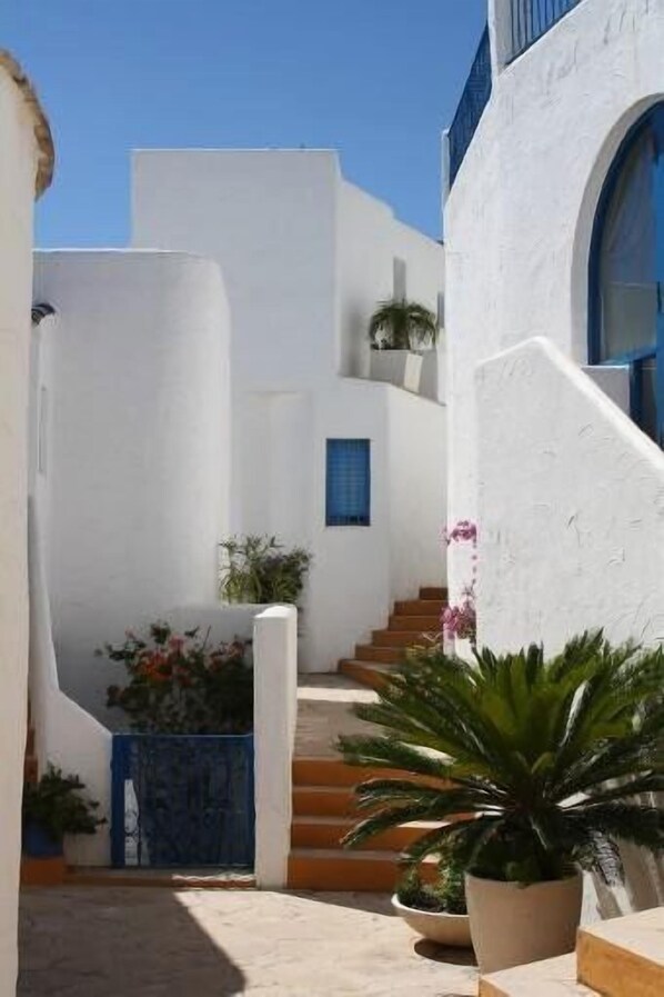 Un bâtiment blanc avec une porte bleue et un escalier menant à un deuxième étage.