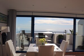 Un balcon avec une table, des chaises et un pot de fleurs.