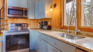 A modern kitchen with stainless steel appliances, granite countertops, and wooden cabinetry. - Stowaway - A Private Lakefront Experience With Over 100ft Of Shoreline! (Lodi)