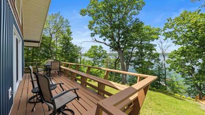 A wooden deck with outdoor furniture, overlooking a lake with trees. - Stowaway - A Private Lakefront Experience With Over 100ft Of Shoreline! (Lodi)