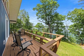 A wooden deck with outdoor furniture, overlooking a lake with trees. - Stowaway - A Private Lakefront Experience With Over 100ft Of Shoreline! (Lodi)