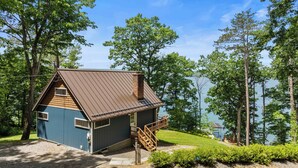 A small cabin with a metal roof, wooden walls, and a wooden staircase leading to a deck. - Stowaway - A Private Lakefront Experience With Over 100ft Of Shoreline! (Lodi)
