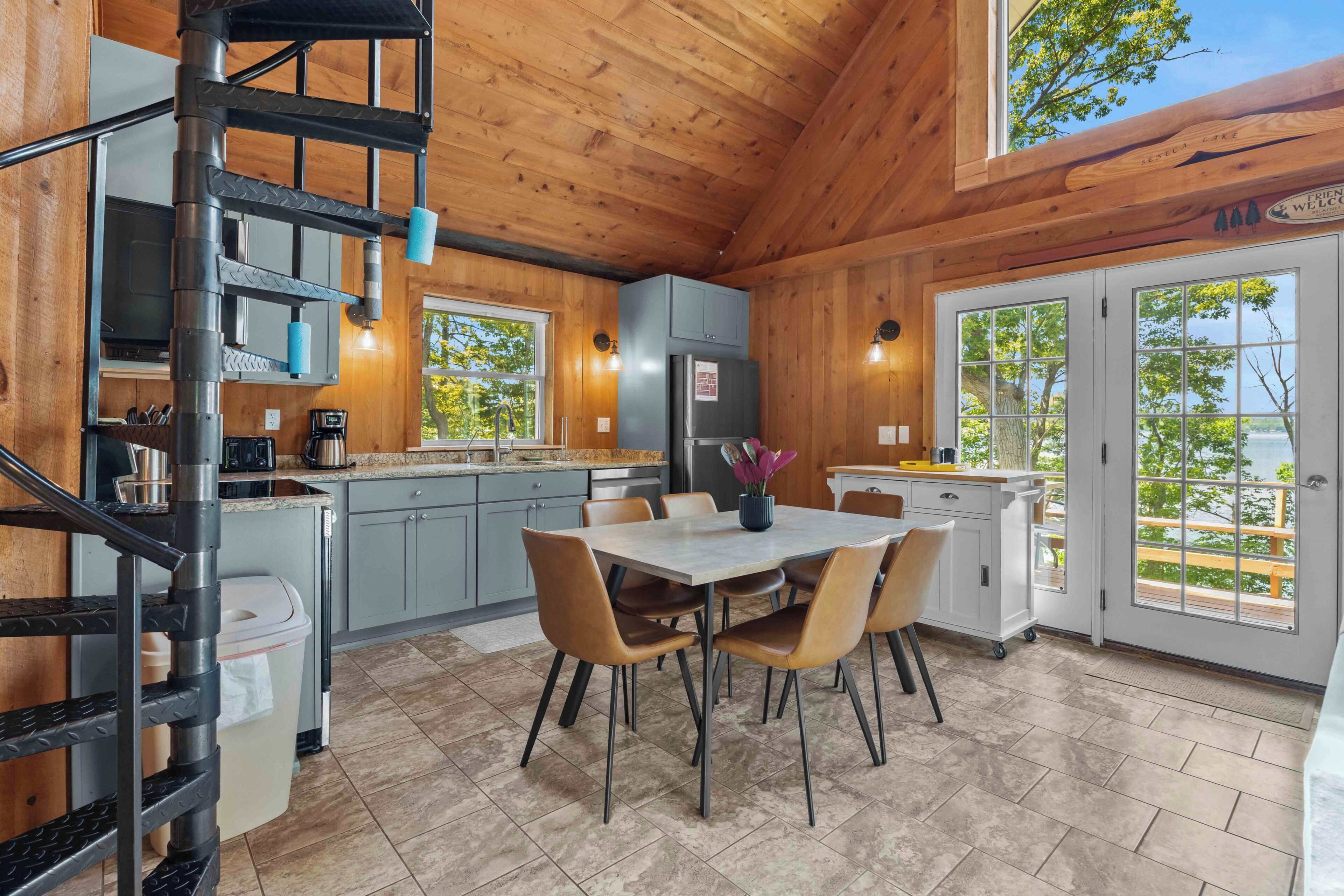 Un intérieur en bois comprenant une cuisine, un coin repas et un escalier en colimaçon.