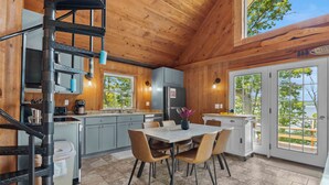 A wooden interior with a kitchen, dining area, and a spiral staircase. - Stowaway - A Private Lakefront Experience With Over 100ft Of Shoreline! (Lodi)