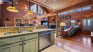 Cozy cabin interior with a high ceiling, stone fireplace, and comfortable seating area.