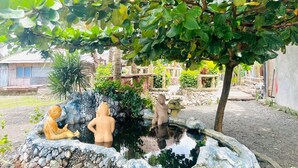 A garden with a stone fountain, three statues, and a variety of plants.