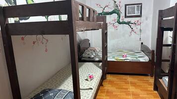 Ein Zimmer mit einem Etagenbett und einem Einzelbett, beide mit Blumenmuster-Bettwäsche.