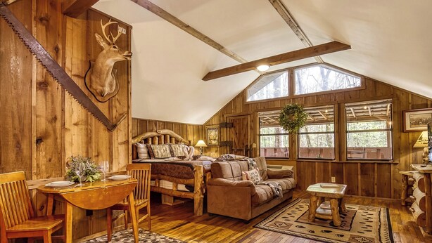 Un intérieur rustique avec une table à manger en bois, un canapé et une tête de cerf accrochée au mur.