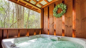 Un bain à remous offrant une vue sur une forêt, grâce à une structure en bois.