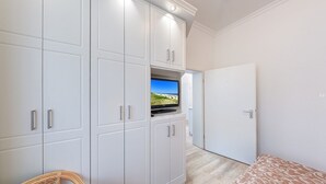A room with a television mounted on a cabinet, a door, and a patterned rug. - Villa Ostseewarte Whg. 6, TERRASSE - Villa Ostseewarte, STRANDNAH, teilw. (Heringsdorf)