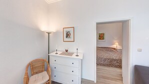 A bedroom with a bed, a dresser, a chair, and two paintings on the wall. - Villa Ostseewarte Whg. 6, TERRASSE - Villa Ostseewarte, STRANDNAH, teilw. (Heringsdorf)