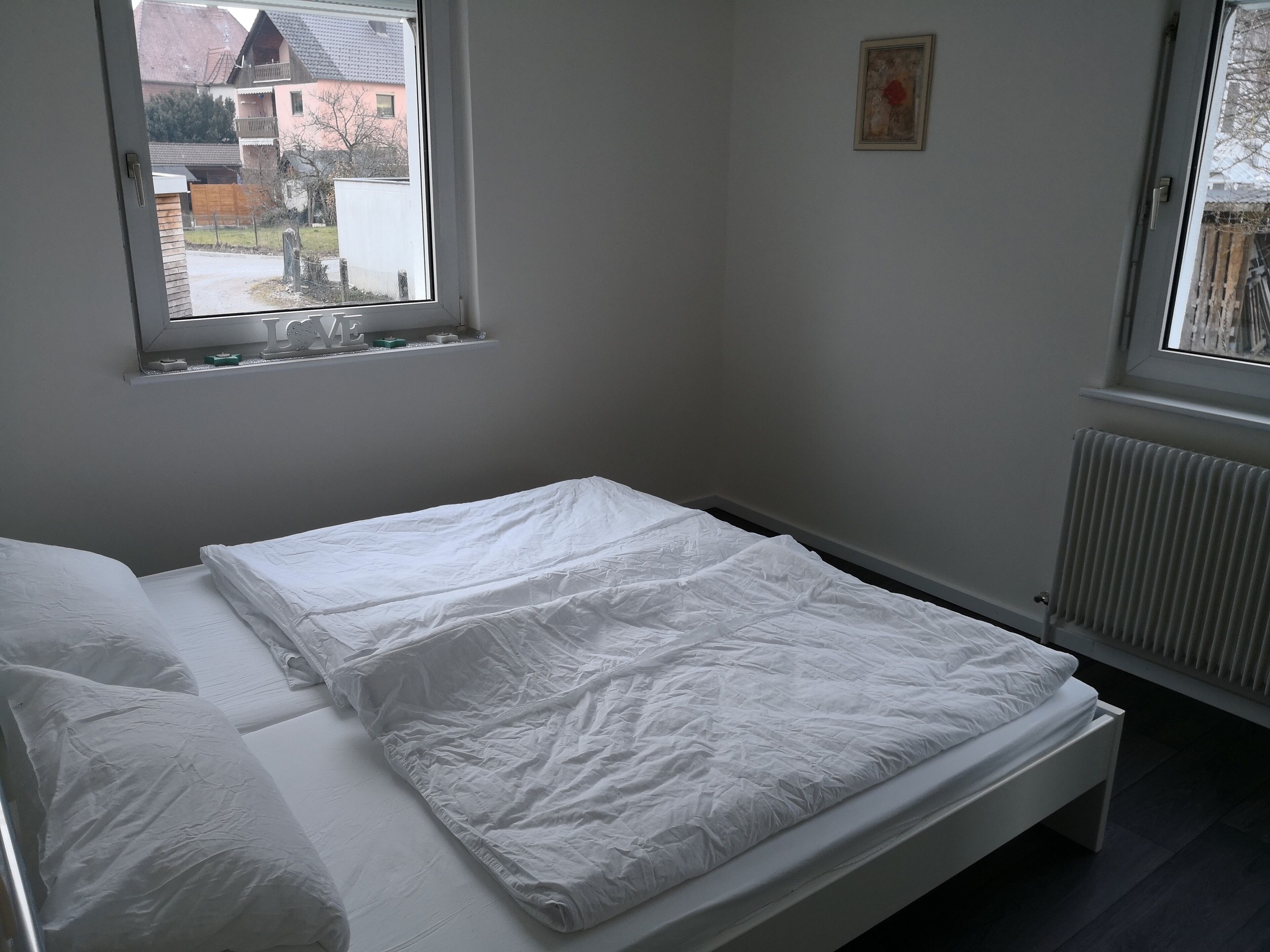 A bedroom with a single bed, a window, and a radiator.