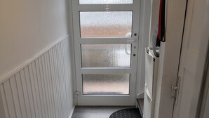 Ein schmaler Flur mit einer weißen Tür, die auf einen Balkon führt.