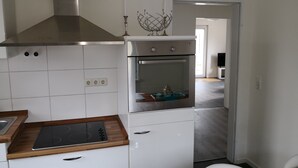 Eine moderne Küche mit weißen Schränken, einer Edelstahl-Dunstabzugshaube, einem eingebauten Backofen und einer Holzarbeitsplatte.