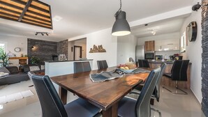 A modern dining area with a wooden table, black leather chairs, and a pendant light.
