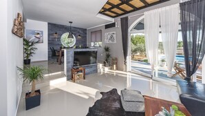 A modern living room with a fireplace, a dining area, and a view of the outdoors.
