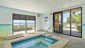 Zona de spa con bañera de hidromasaje, vista a la playa y un cartel que indica que está prohibido bucear.