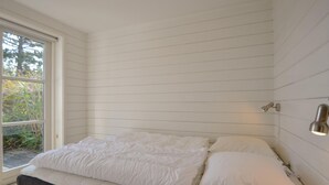 A bedroom with a bed, a window, and a wall-mounted light fixture.