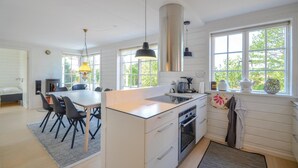 A modern kitchen with a central island, white cabinetry, and large windows.
