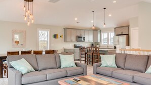 A modern living room with two grey sofas, a wooden coffee table, and a dining area with wooden chairs and a table. - Good To Be Back: Soundside, Private Pool & Spa, Great Community Amenities (Corolla)