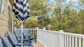 A wooden deck with three blue Adirondack chairs and a striped umbrella. - Good To Be Back: Soundside, Private Pool & Spa, Great Community Amenities (Corolla)