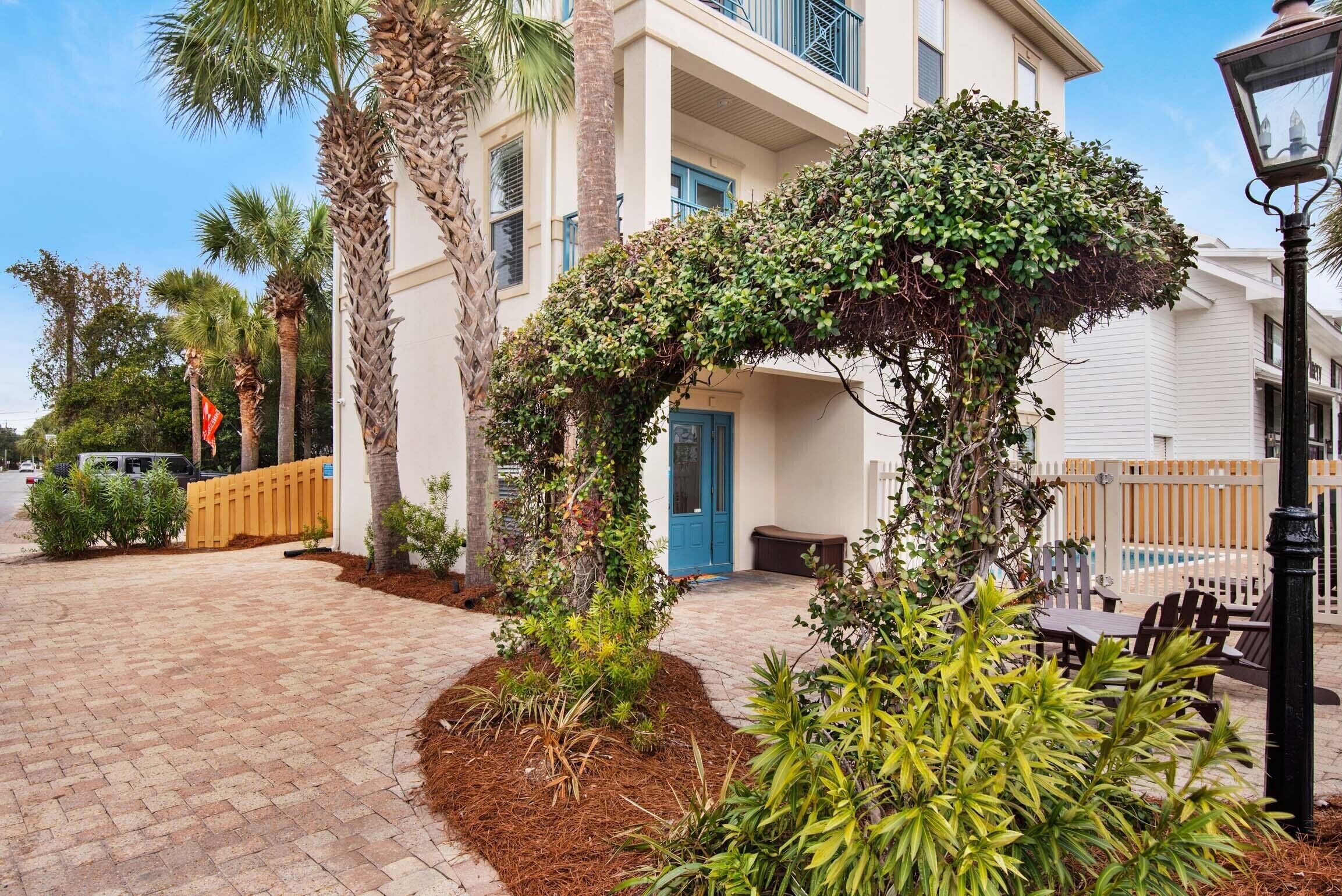A building with a blue door, surrounded by palm trees and a brick pathway.