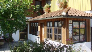 A wooden building with a tiled roof, large windows, and flower boxes on the upper floor. - Appartementhaus Weber (Arrach)