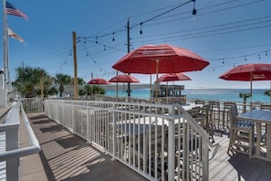 Eine Terrasse mit Sitzgelegenheiten und roten Sonnenschirmen mit Blick auf einen Strand.