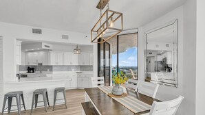 A modern kitchen with white cabinets, a wooden dining table, and a view of the outdoors. - Free Beach Svc=2 Chairs/1 Umbrella! Awesome Views! Free Beach Bonfires M/F nts (Miramar Beach)