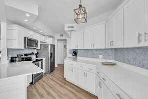 Una cocina moderna con armarios blancos, electrodomésticos de acero inoxidable y un salpicadero de baldosas en patrón de espiga.