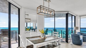 A modern dining area with a view of the ocean, a large window, and a dining table with chairs.