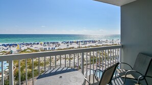A balcony with a view of a beach, featuring a pool table and chairs.