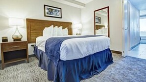 A hotel room with a bed, nightstands, a lamp, a mirror, and a door leading to a balcony.