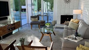 Una sala de estar moderna con un sofá, sillas, una mesa de centro, una chimenea y un televisor.