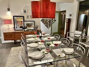 Un comedor con una mesa de vidrio, sillas transparentes y una cortina roja.