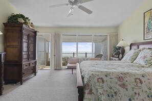 Ein Schlafzimmer mit einem großen Bett, einem Deckenventilator, einer Kommode und Blick ins Freie.
