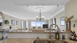 A kitchen with granite countertops, a double sink, a chandelier, and a view to the living area. - GORGEOUS OCEAN FRONT MULTI LEVEL CONDOMINIUM! (Atlantic Beach)