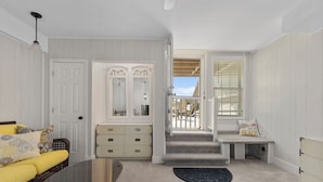 A room with a bed, a bench, a dresser, and a staircase leading to an outdoor area. - GORGEOUS OCEAN FRONT MULTI LEVEL CONDOMINIUM! (Atlantic Beach)