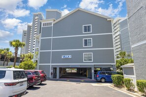 A multi-story hotel with a sign reading 'VILLA I' and a parking area with several cars. - Oceanfront Views from Every Room in This Condo (Myrtle Beach)