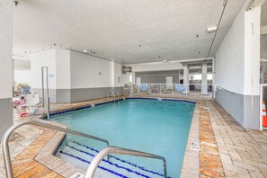 An indoor swimming pool with clear water, a tiled deck, and a metal pool ladder. - Oceanfront Views from Every Room in This Condo (Myrtle Beach)