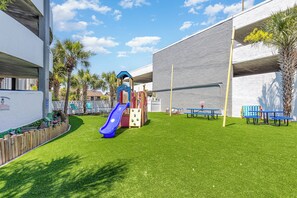 A playground with a slide and climbing structures, surrounded by a grassy area and benches. - Oceanfront Views from Every Room in This Condo (Myrtle Beach)