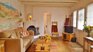 Una sala de estar acogedora con un sofá, una chimenea, un televisor y un cuadro en la pared.