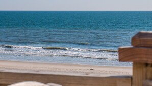 Una playa con una valla de madera en primer plano y una vista despejada del océano.