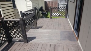 A wooden deck with a metal railing, leading to a fenced area with a grill. - The Mountain House at the base of Mount Shasta (McCloud)